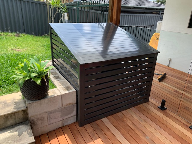 Black pool filter cover installed on a beautiful timber deck